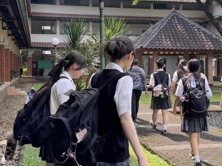 SMA Dwiwarna の校舎と中庭の間を歩く日本の生徒